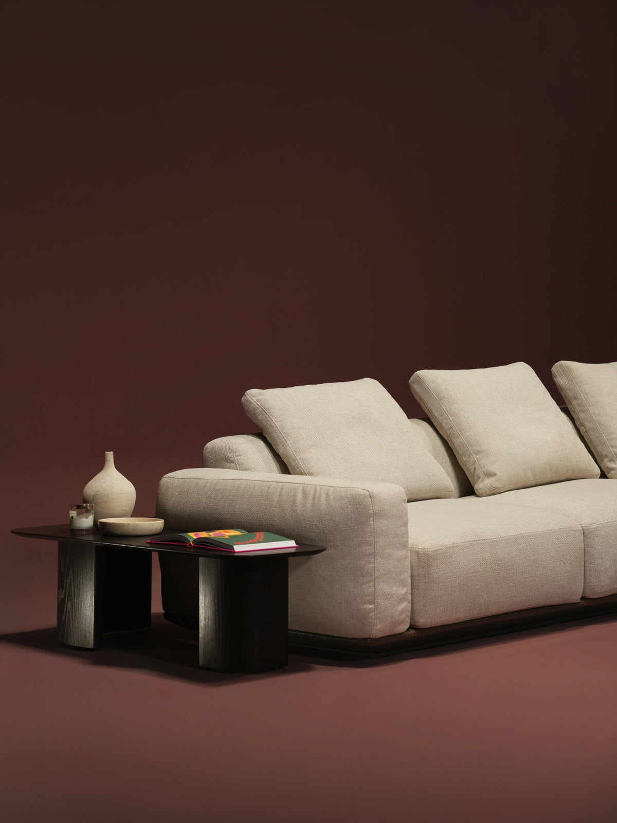 Close-up of the beige Soffio sofa with tall seat cushions, duck feather-filled back cushions, and a leather upholstered platform.