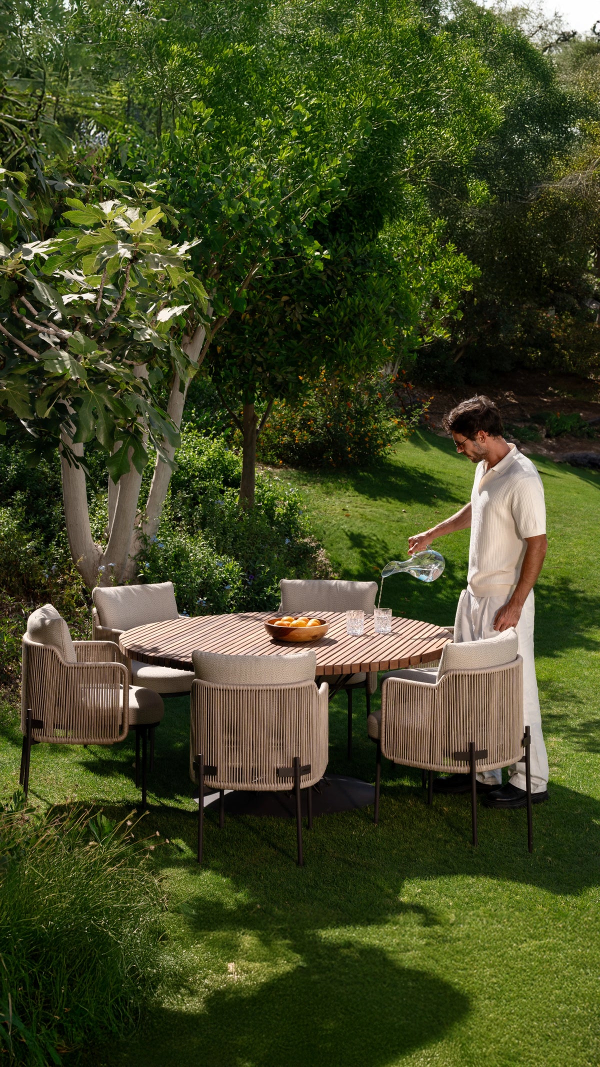 Spiral dining table styled outdoors surrounded by Cord chairs rope-back frame with cream upholstery.
