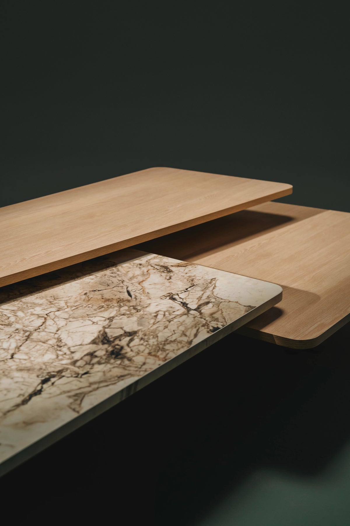 Close-up of the Trio coffee table’s three overlapping tops, combining marble laminate and light wood veneer at different heights.
