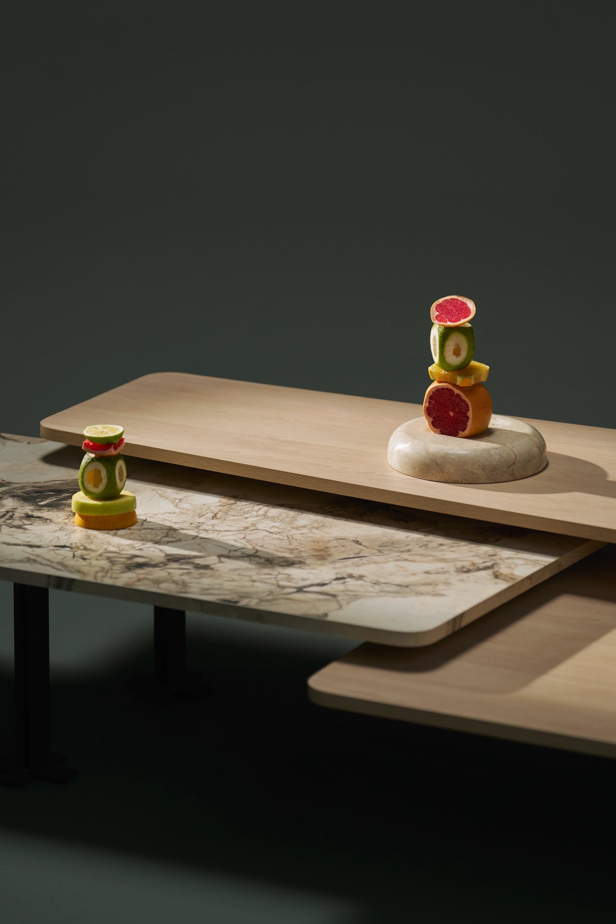 Close-up of the Trio coffee table’s layered wood veneer and marble laminate tops, arranged at fixed staggered heights.