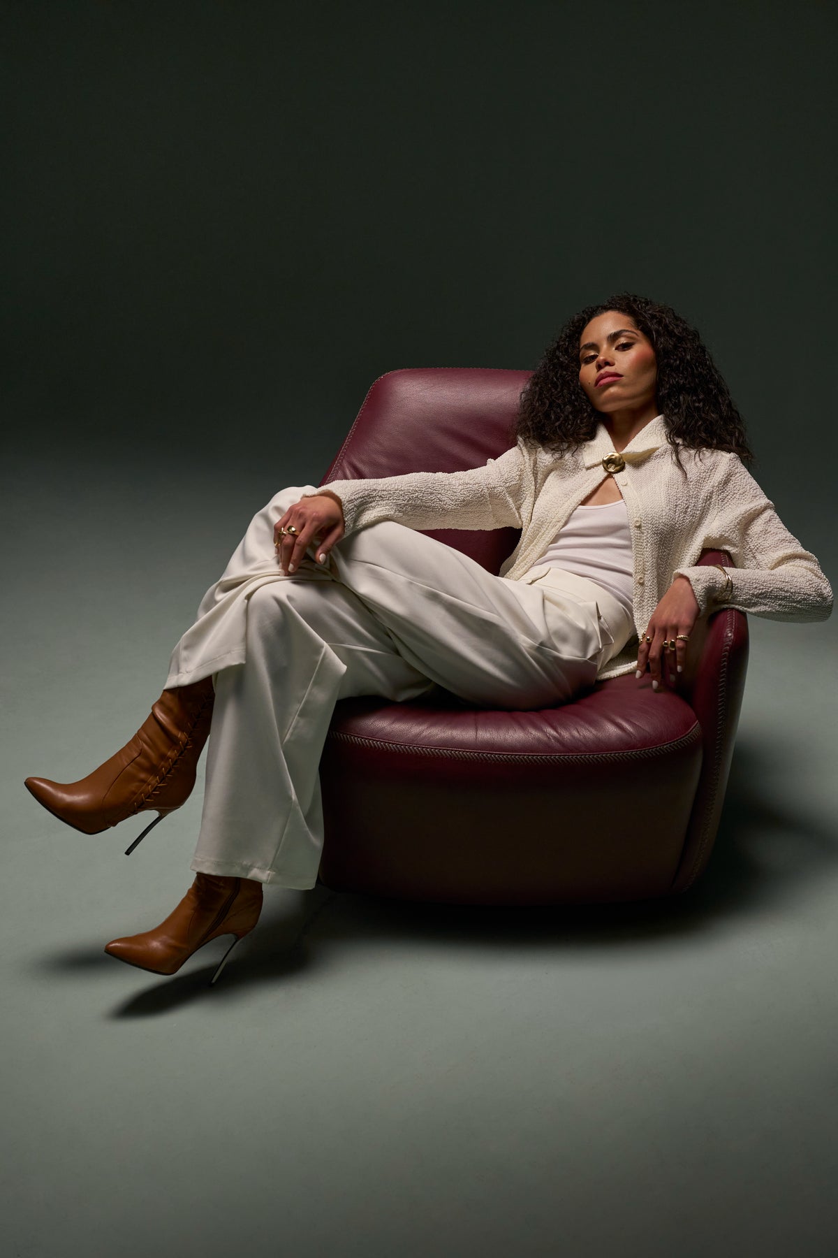Model seated on Windsor Low armchair in burgundy genuine leather, styled with low backrest and enveloping arms.