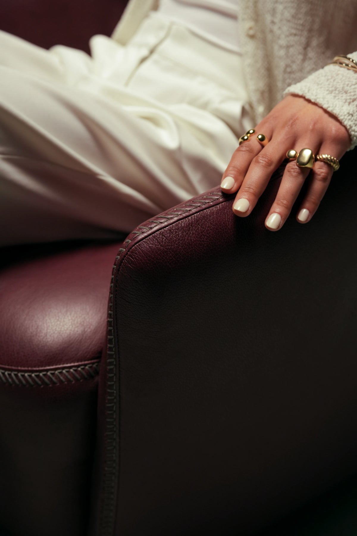 Close-up of the burgundy leather Windsor Low armchair, highlighting the overcast seam along its rounded arm and seat.
